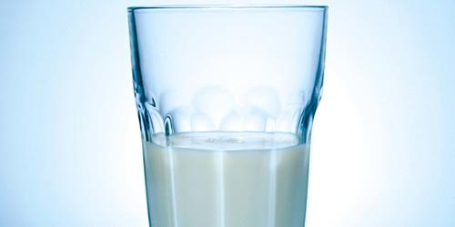 a half full glass on milk on a white background